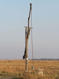 Wooden post on field against clear sky