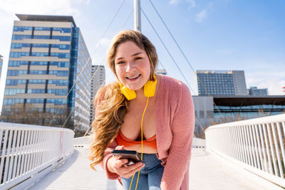 Portrait of young woman photographing in city