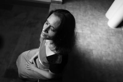 High angle view of mature woman sitting on retaining wall