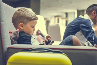 Cute boy holding joystick while sitting of sofa at hotel