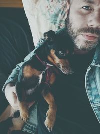 Portrait of man holding puppy at home