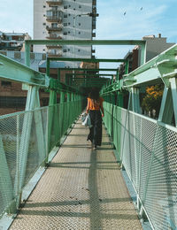 Woman walking on footbridge in city