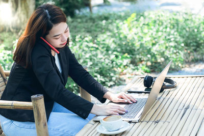 Woman using mobile phone while sitting on table