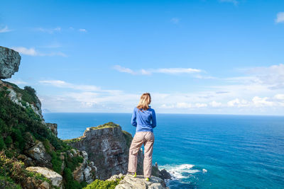 Rear view of woman standing on mountain by sea at cape point