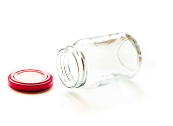 Close-up of glass jar with bottle against white background