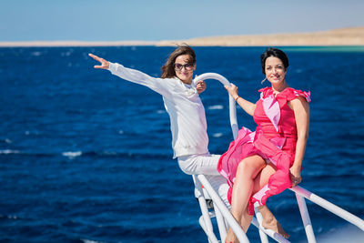 Two women relaxing together on the nose of the yacht at sunny summer day at sea