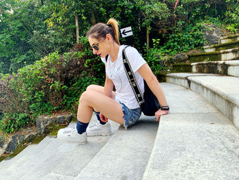 Side view of a smiling young woman sitting on staircase