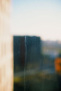 Close-up of wet window against sky