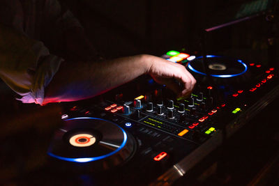 Hands of dj tweak various track controls on dj sound mixer