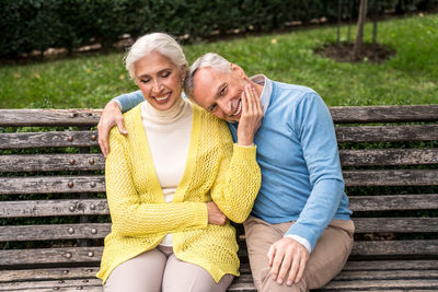 Smiling couple sitting on bench at park