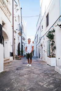 Full length portrait of young man standing against white wall