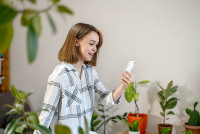 Young smiling woman having video call on smartphone at home. girl greeting friends on a video chat.