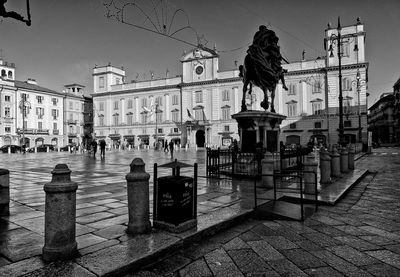 Statue at town square by historic building against clear sky