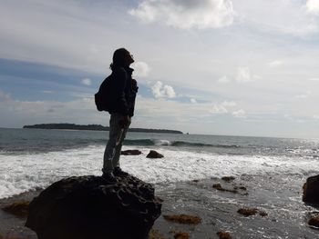 Young man standing on rock at beach