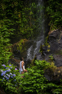 Rear view of man sitting on rock