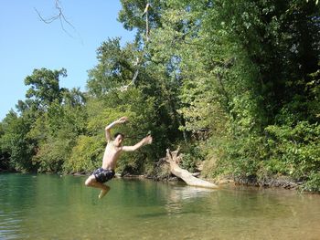 Full length of shirtless man jumping in lake