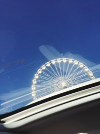 Low angle view of illuminated ferris wheel against blue sky