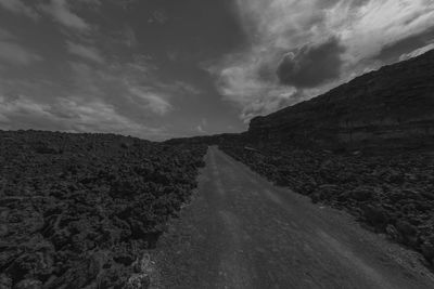 Road leading towards mountain against sky
