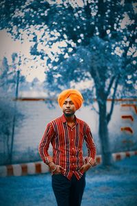 Portrait of young man standing against trees