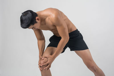 Full length of shirtless man standing against white background