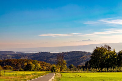 Road amidst field against sky