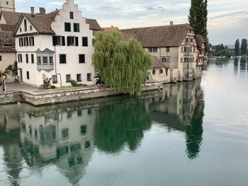 Houses by lake and buildings against sky