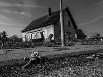 Man by house on field against sky
