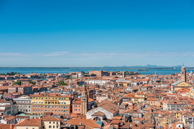 High angle view of townscape by sea against blue sky