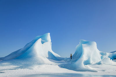 Unrecognizable traveler hiker admiring spectacular scenery of frozen seashore with ice and snow in winter in iceland