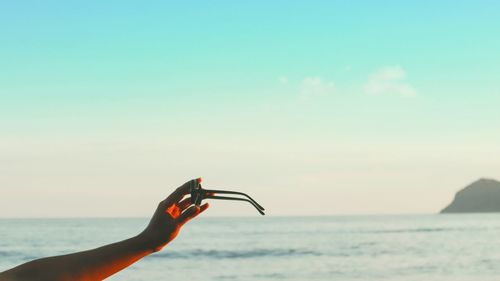 Midsection of person holding sea against sky