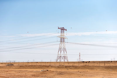 Low angle view of electricity pylon on field against sky