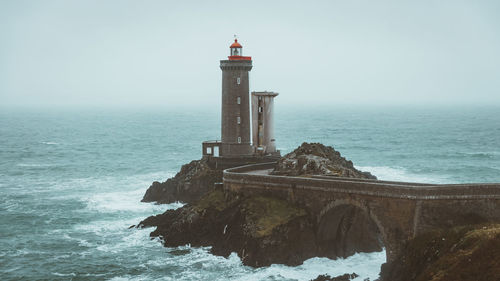 Lighthouse by sea against sky