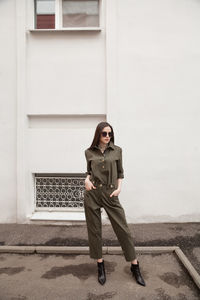 Female fashion model, posing for a full length photo, wearing green suit, urban fashion photography