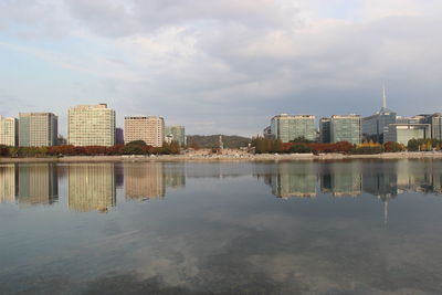 Buildings by river against sky in city