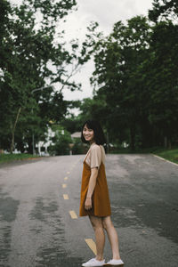 Woman standing on road by trees
