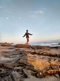 Full length of woman standing on rock at beach