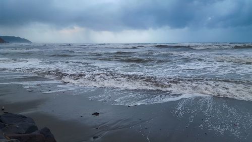 Scenic view of beach against cloudy sky