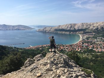 Man standing on rock against sky