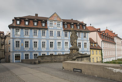 Statue of queen kunigunde and a blue house on the alte rathaus bridge in bamberg