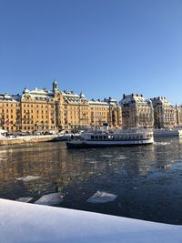 Buildings at waterfront against blue sky