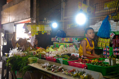 People sitting at illuminated market stall at night