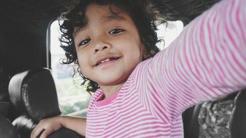 Close-up portrait of cute girl with curly hair sitting in car