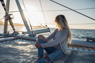 Woman sitting on boat against sea at sunset