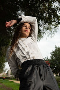 Portrait of young woman standing against trees