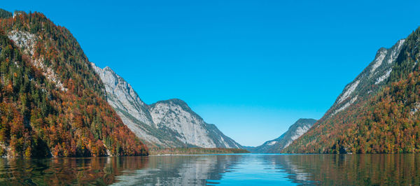 Panoramic view of lake and mountains against clear blue sky