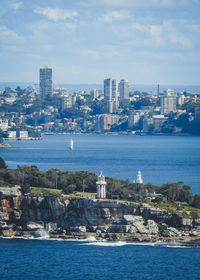 Buildings at waterfront against cloudy sky