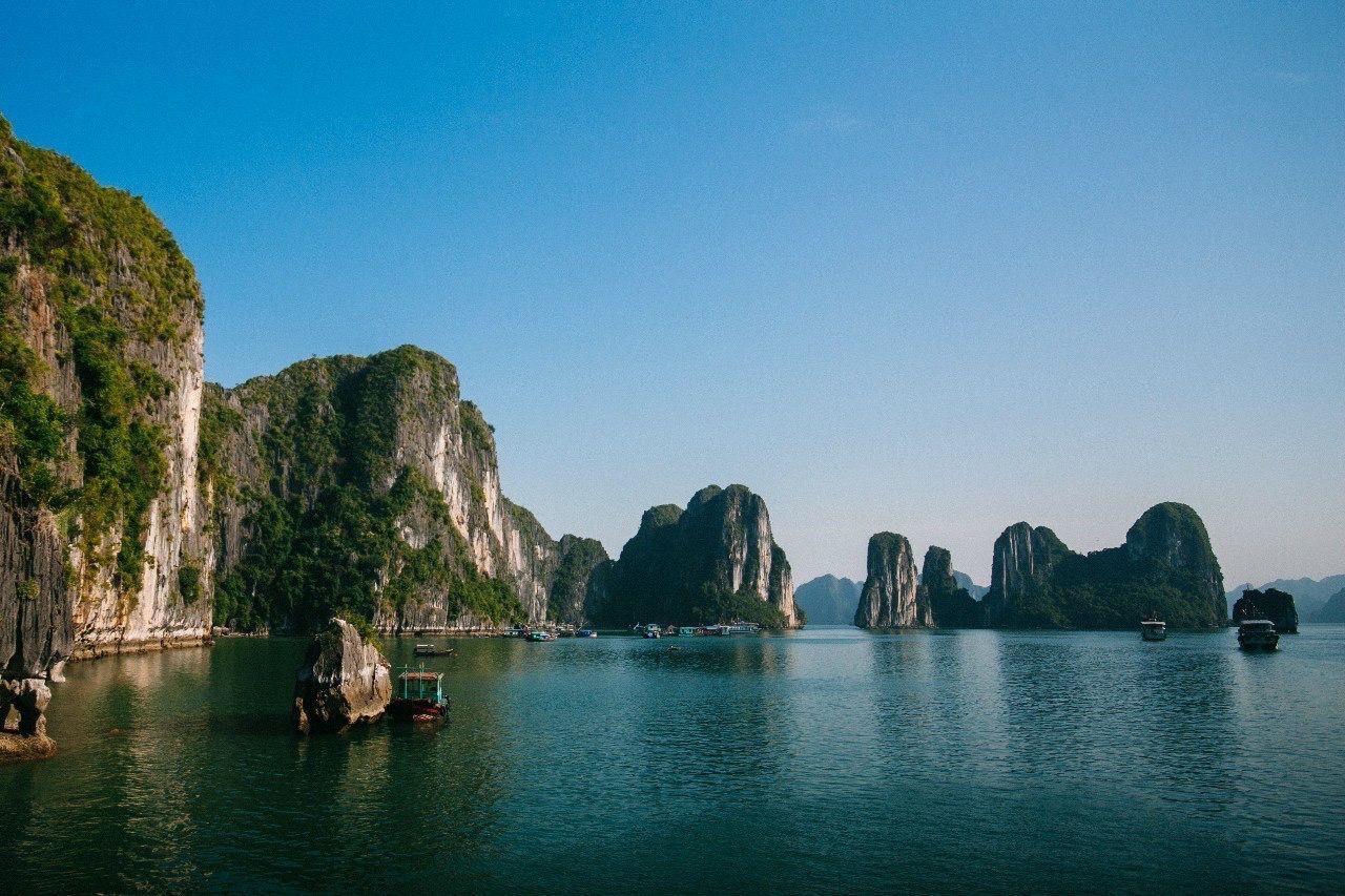 water, nautical vessel, clear sky, transportation, waterfront, mountain, mode of transport, copy space, tranquility, scenics, tranquil scene, boat, beauty in nature, blue, nature, sea, lake, rock formation, river