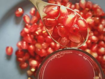 Close-up of pomegranate seeds in spoon over juice