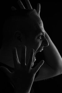 Close-up of man shouting against black background