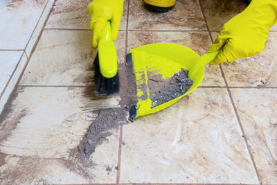 Person wearing gloves cleaning dust with duster at home